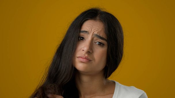 Close up depressed Indian woman girl female lady brunette looking at split ends of hairstyle worried feels upset about brittle damaged dry hair loss alopecia hormone problems or vitamins deficiency - Photo, image
