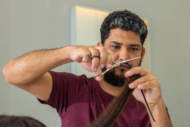 A hairdresser cutting the ends of a client's hair using scissors. - Foto, Imagen