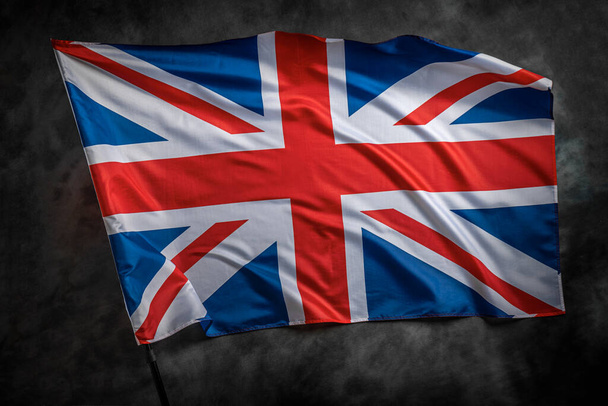 İngiltere bayrağı rüzgarda dalgalanırken karanlık bir arkaplanda. - Fotoğraf, Görsel