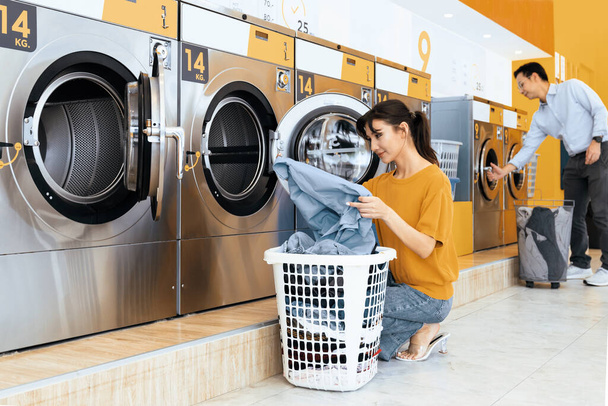 Les Asiatiques qui utilisent une machine à laver à pièces qualifiée dans la salle publique pour laver leurs draps. Concept d'une laveuse et sécheuse commerciale en libre-service dans une salle publique. - Photo, image