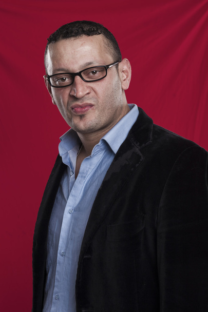 Portrait d'homme fronçant les sourcils portant des lunettes sur fond rouge
 - Photo, image