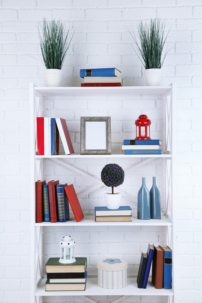 Bookshelves with books and decorative objects on brick wall background - Foto, imagen