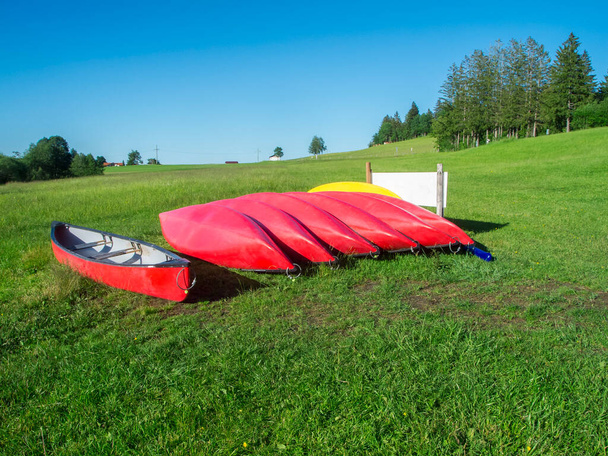 View of a row of red kayaks on a sloping meadow at Lake Gruenten in Bavaria in summer. - Foto, Bild