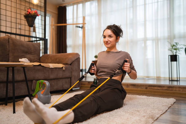 One woman beautiful caucasian female training at home in room using rubber resistance bands tubes sportswoman doing exercises alone health and fitness concept copy space - Photo, Image
