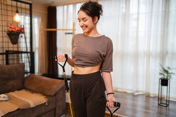 One woman beautiful caucasian female training at home in room using rubber resistance bands tubes sportswoman doing exercises alone health and fitness concept copy space - Foto, Imagem