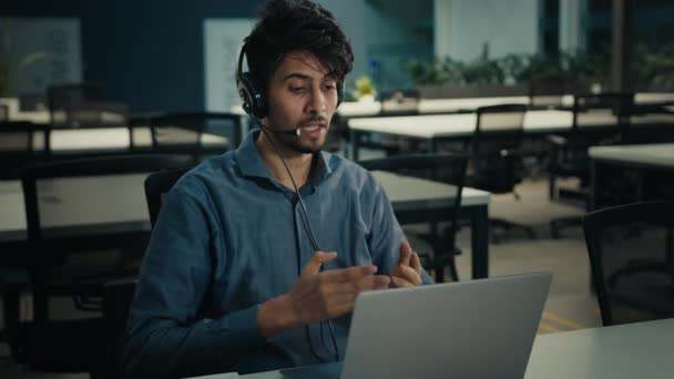 Indian man internet teacher lawyer expert businessman in headphones sit at office talking video conference online call on laptop support client distant hold business documents telemarketing profession - Video, Çekim