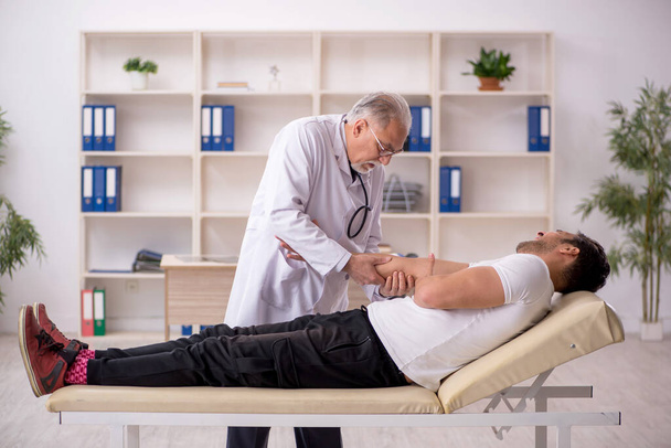 Young doctor visiting old doctor chiropractor - Foto, Imagen