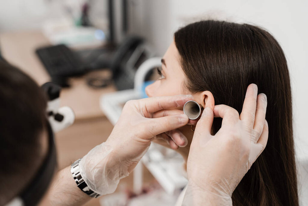 Διαβούλευση με ωτορινολαρυγγολόγο. Θεραπεία του πόνου στο αυτί της γυναίκας. Οτοσκόπηση των αυτιών με χωνί αυτιού. ΩΡΛ γιατρός με ωτοσκόπιο - Φωτογραφία, εικόνα