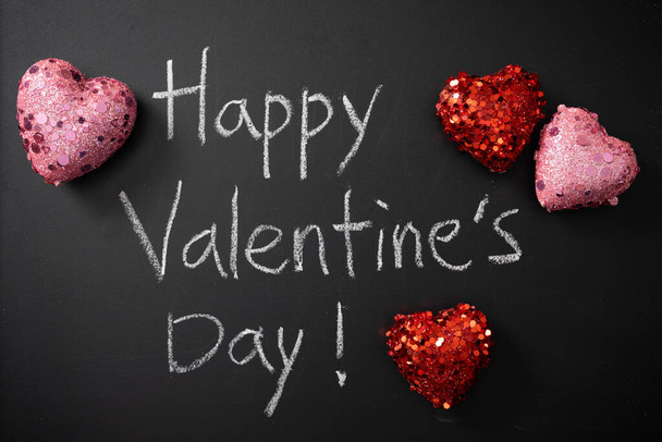 Happy Valentines Day written in chalk on blackboard with glittery pink and red heart - Fotografie, Obrázek