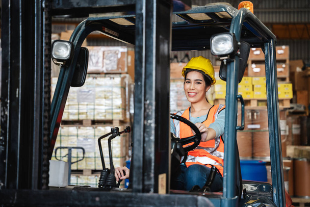 Portrait of a woman working with a forklift in a warehouse with her looking at the camera. - Фото, зображення