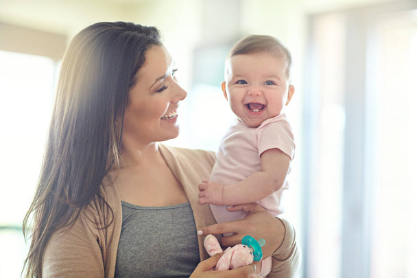 Mother, carrying or laughing baby girl in house living room, nursery or family home bedroom in trust, love or support. Smile, happy mom or infant child in funny, goofy and comic bonding game for kids. - Fotografie, Obrázek