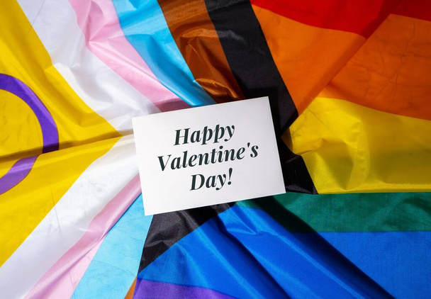 HAPPY VALENTINES DAY text Greeting card on Rainbow LGBTQIA flag made from silk material. Symbol of LGBTQ pride month. Equal rights. Peace and freedom. Support LGBTQIA community. Diversity equality - Photo, Image