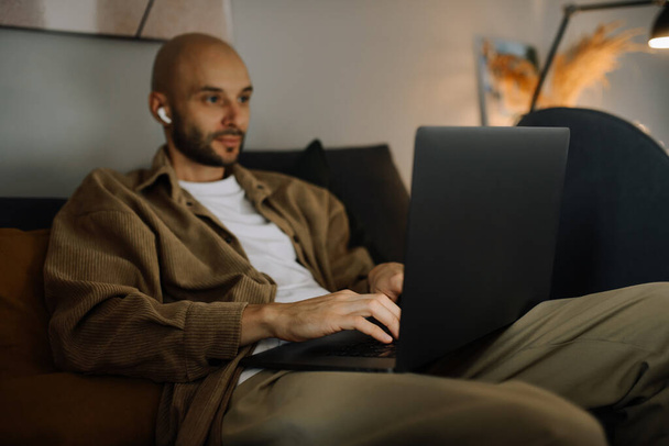 男は自宅のオフィスのノートパソコンでヘッドフォンで動作します。フリーランス、ビジネスマン、 IT専門家、学生. - 写真・画像