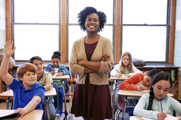 Portrait, student question and black woman teacher in classroom or middle school. Education, arms crossed or boy raising hand to answer questions, studying or learning help with happy female educator. - Foto, Imagen