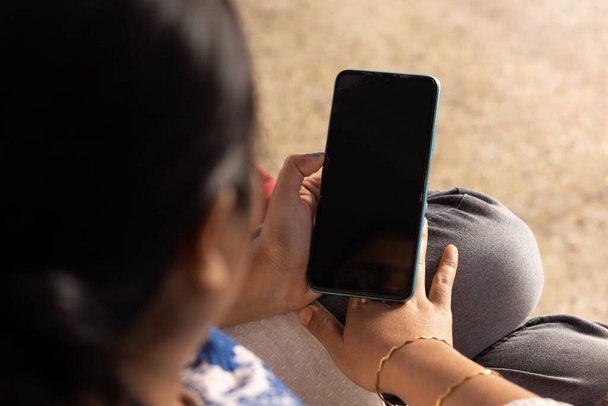Індійська жінка з розумним телефоном дивиться на чистий чорний екран у руці вдома. - Фото, зображення