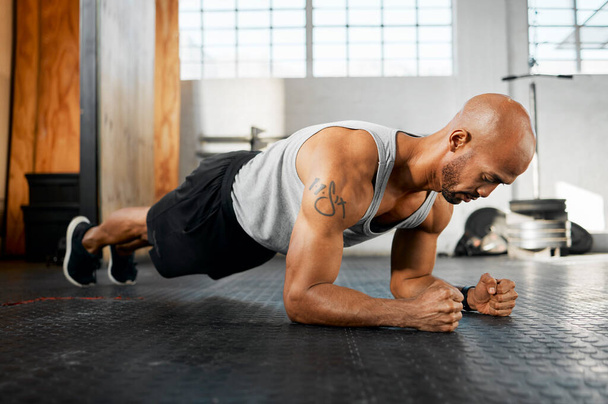 A strong body makes for a strong mind. a young man completing a plank session - Foto, Imagen