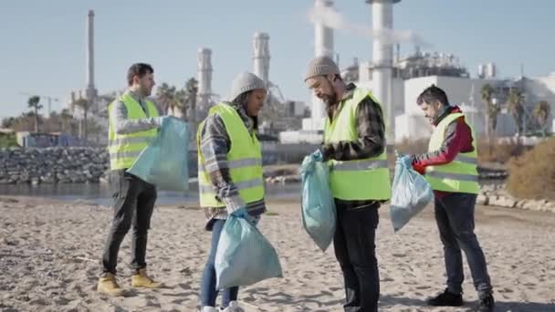 Группа людей, работающих вместе для очистки промышленных отходов на берегу реки - Охрана окружающей среды - Кадры, видео
