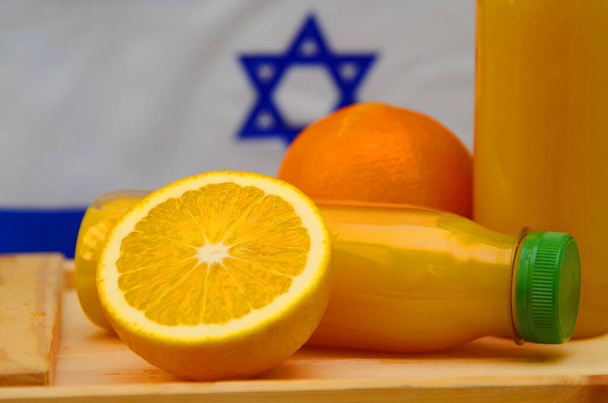 Plastic bottle with fresh juice. The flag of Israel is in the background. Concept: Israeli orange juice, Middle Eastern oranges - Foto, Imagem