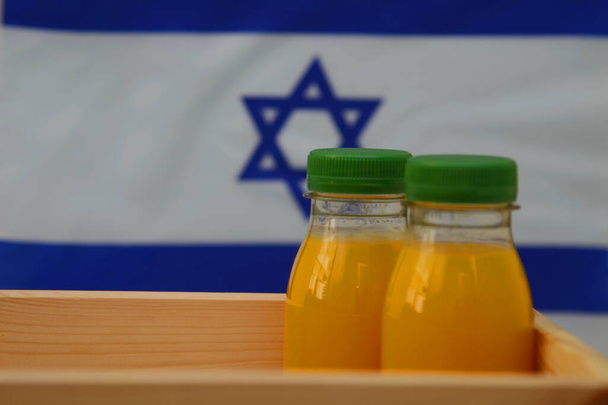 Plastic bottle with fresh juice. The flag of Israel is in the background. Concept: Israeli orange juice, Middle Eastern oranges - Photo, image