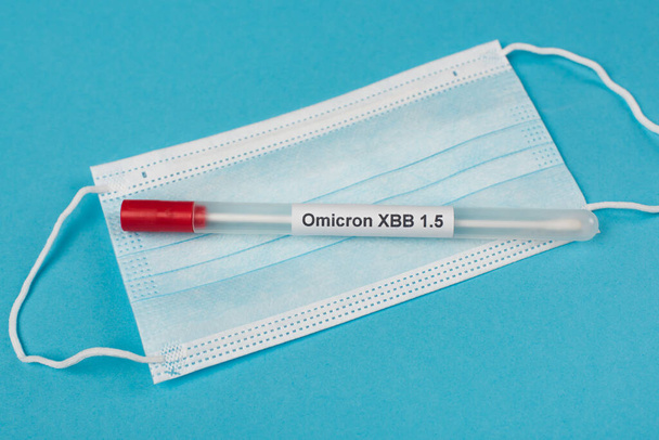 Top view of cotton swab with omicron xbb lettering on medical mask on blue background  - Photo, Image