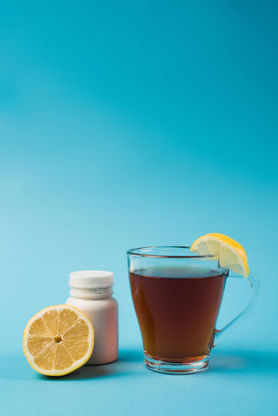 Cup of tea near lemon and cut lemon on blue background  - Foto, immagini