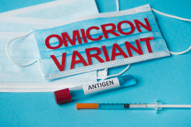 Test tube with antigen lettering near medical masks and syringe on blue background  - Fotografie, Obrázek