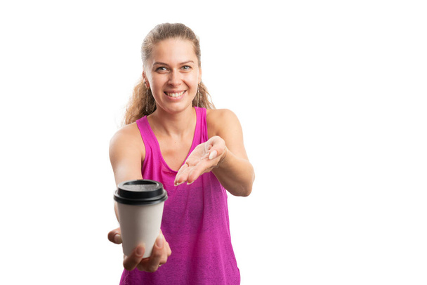 Friendly sportive female model wearing fitness training attire presenting paper cup of coffee as morning healthy fitness lifestyle concept with blank copyspace isolated on white background - Foto, imagen