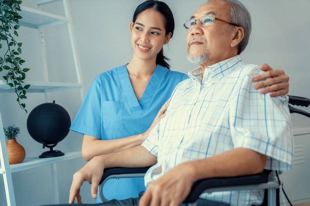 Caring nurse and a contented senior man in a wheel chair at home, nursing house. Medical for elderly patient, home care for pensioners. - Photo, Image