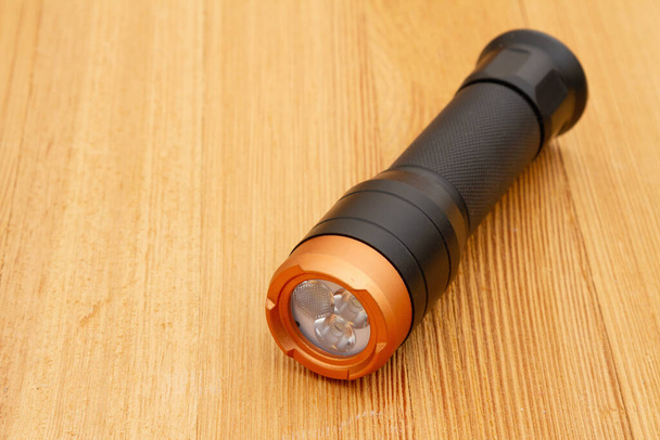 Black and bronze LED flashlight on wood table for your emergency ready kit - Fotó, kép