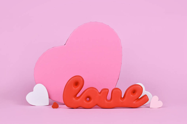 Valentine's Day decoration with red word love, gift box and heart ornaments on pink background - Foto, Imagen