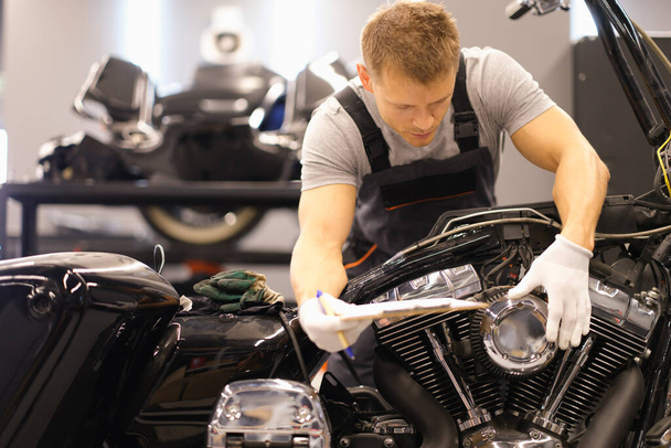 Master diagnoses and repairs motorcycle in workshop. Motorcycle maintenance concept - Photo, Image