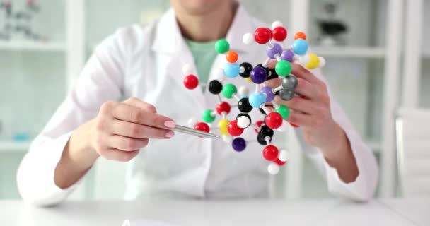 Woman scientist holds model of molecular compounds in hands. Study of human genome and conceptual scientific chemical innovation - Filmati, video