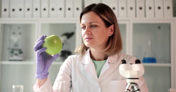 Scientist examines green apple for presence of GMO products in laboratory. Studying presence of nitrates in foods - Video