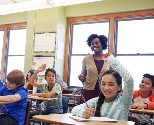 Освіта, вчитель і діти піднімають руки, щоб поставити або відповісти на академічне питання для навчання. Різноманітність, школярі та діти початкової школи розмовляють зі своїм викладачем у класі
 - Фото, зображення