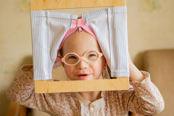 A girl with Down syndrome develops fine motor skills. Self-service skills Zip up clothes - Zdjęcie, obraz