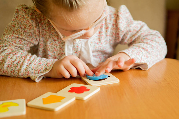 A girl with Down syndrome develops fine motor skills. learning to assemble puzzles - Foto, Imagem