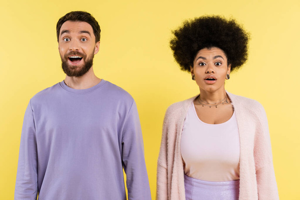 surprised bearded man and curly african american woman standing with open mouth isolated on yellow - Photo, Image
