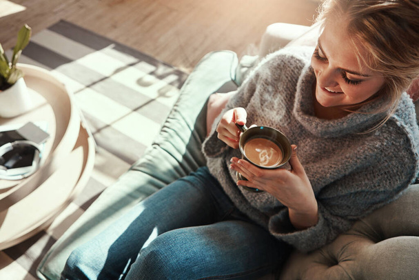 Woman, coffee and relax smile on sofa in living room for calm, peace and happy quality time. Female, drinking warm tea and happiness or lifestyle wellness, morning routine and rest on couch in home. - Foto, afbeelding