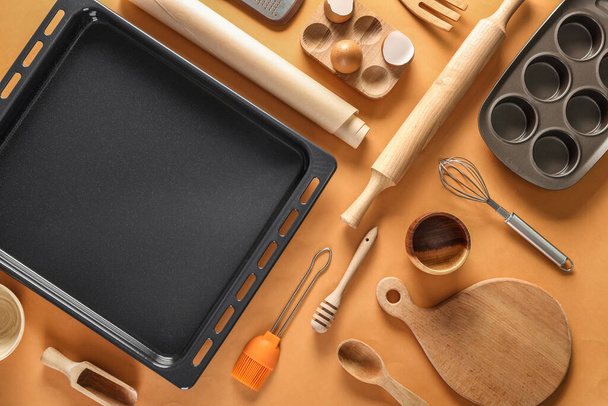Baking tray with utensils on orange background - Zdjęcie, obraz