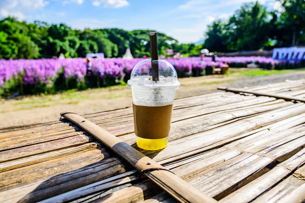 Fresh ice tea in plastic glass with flower garden, Chiang Mai province. - Valokuva, kuva