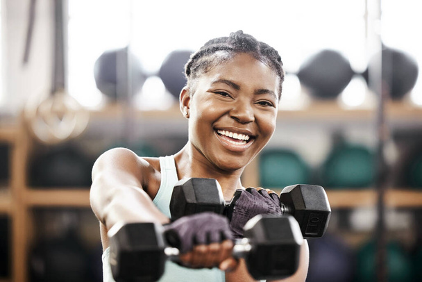 Learn to have fun while working out. an attractive young woman standing alone in the gym and using dumbbells during her workout - Valokuva, kuva