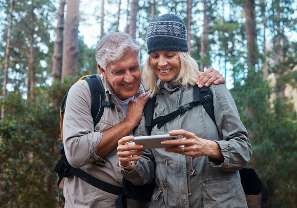 We took some great pictures. a mature couple using a cellphone while out on a hike together - Фото, изображение