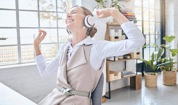 Music, headphones and senior business woman dance in office, happy and excited about small business. Earphones, dancing and elderly female celebrate in design studio, cheerful and positive at a desk. - Zdjęcie, obraz