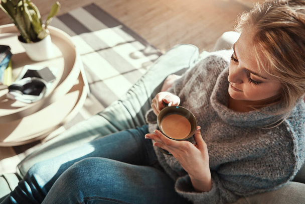 Woman, coffee and calm on sofa in living room for peace and relaxing quality time. Female, drinking warm tea and thinking for lifestyle wellness vision, morning routine and rest on couch in home. - Foto, Bild