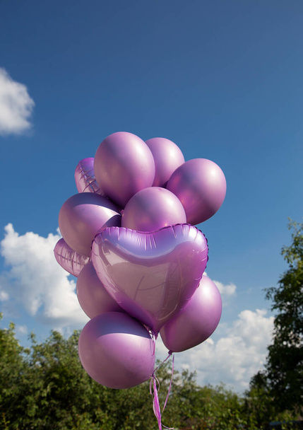 bunch of one-color purple-pink helium balloons against the sky. The concept of joy, freedom, positivity and congratulations. festive mood, surprise, preparation for a party - Foto, Imagen