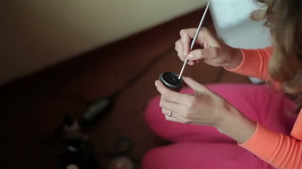 Dziewczyna z długie kręcone włosy za pomocą makijażu pędzel - Materiał filmowy, wideo