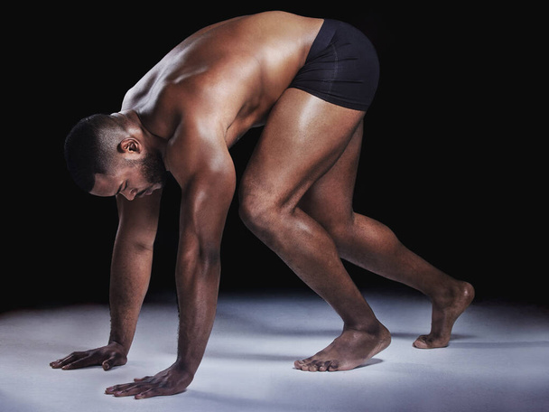 Surrender to desire. Studio shot of a young fit man stretching against a black background - Foto, Bild