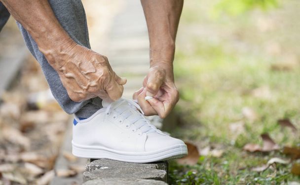 靴ひもを結ぶ老人は運動の準備をします高齢者の転倒の危険を防ぐという概念 - 写真・画像