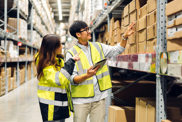Asian two engineer team shipping order detail on tablet check goods and supplies on shelves with goods background inventory in factory warehouse.logistic industry and business export - Zdjęcie, obraz