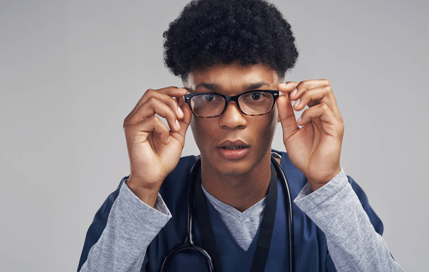 I see the problem...a male nurse wearing glasses while standing against a grey background - Foto, Imagen